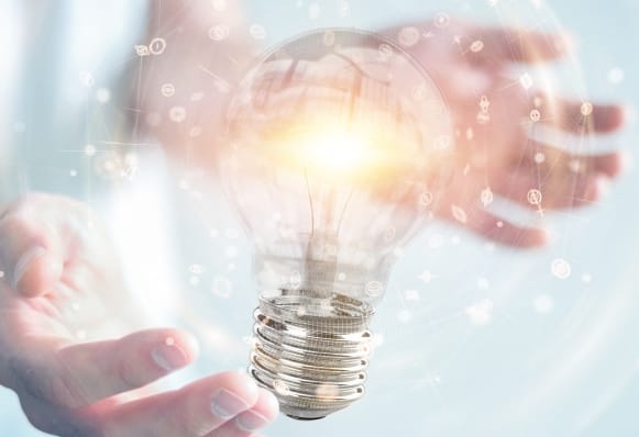 両手の間に浮かぶ発光する電球のイメージ